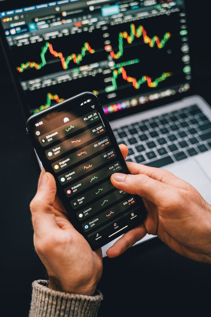 about-us-02 Hands holding smartphone with stock app, laptop displaying charts. Perfect for financial and technology themes.